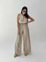 Conjunto de musculosa y pantalón palazzo color dorado brillante. La musculosa es sin mangas y el pantalón es de corte ancho con cintura alta.