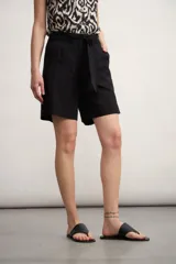 Short negro de tiro alto con lazo de tela para ajustar en la cintura y bolsillos laterales. El largo es por encima de la rodilla.