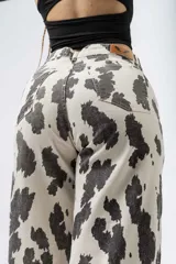 Pantalón wide leg con estampado de vaca en blanco y negro, de tiro alto y cierre de botón y cremallera.