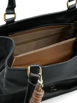 Cartera de mano color negro con textura granulada, diseño estructurado, doble asa superior y detalle de colgante decorativo con nudo en tono nude.