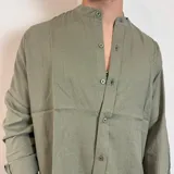 Camisa de lino color verde militar, de manga larga con puños doblados, cuello mao y cierre frontal con botones.
