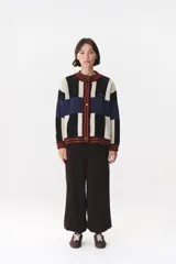 Cardigan de punto con diseño de bloques de color en tonos marrón, beige y verde. Presenta cuello redondo, cierre frontal con botones, mangas largas con hombros caídos y logo bordado en el frente.