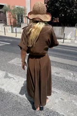 Vestido midi marrón con cuello solapa, escote en pico, mangas cortas con vuelta y cierre frontal con botones. Incluye un cinturón ancho a juego con hebilla metálica rectangular.