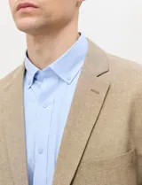 Blazer de medio forro, color marrón tostado, con solapas de muesca, cierre frontal de dos botones y bolsillos con solapa. Presenta silueta estructurada.
