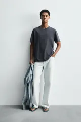 Camiseta relaxed fit de algodón ligero, color gris oscuro, con cuello redondo y manga corta con acabados irregulares. Pertenece a la colección especial Origins.