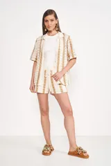 Camisa beige de tejido crochet a rayas verticales color dorado, con cuello camisero y mangas cortas.