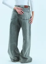 Jean de corte oversize con tiro medio-alto, confeccionado en denim de algodón con lavado tipo ice wash en tono grisáceo. Presenta diseño de cinco bolsillos, cierre frontal y etiqueta de cuero en la parte posterior de la cintura.