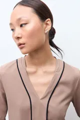 Remera de manga larga color tostado con escote en V y detalles de vivos en contraste color negro que recorren el frente y los laterales de las mangas.