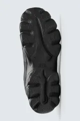 Zapatillas grises con cordones, suela con volumen y diseño irregular.