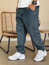 Pantalón tipo carpenter de denim azul con corte holgado, bolsillos laterales utilitarios y cierre frontal con botón.