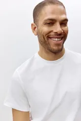 Remera blanca de algodón liviano con cuello redondo ribeteado y bajo recto. Corte estándar.