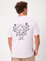 Remera blanca Rusty de corte holgado, con cuello redondo y mangas cortas. Presenta un estampado en la espalda de estilo veraniego con palmeras, una tabla de surf y letras alusivas a la marca.