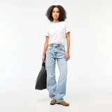 Pantalón jean de corte globo y tiro alto, en tono azul claro con efecto lavado. Presenta diseño amplio de perneras curvas y costuras decorativas.