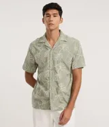 Camisa de calce comfort de la marca Marfinno, confeccionada en algodón color verde con bordado de hojas blancas. Posee cuello con solapa, manga corta y cierre frontal con botones.