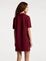 Vestido corto de estilo polo confeccionado en tejido de punto piqué, color bordó. Presenta cuello clásico, escote con abertura y mangas cortas.