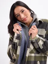 Sobrecamisa de corte holgado con estampado de cuadros en tonos azul, blanco y marrón. Presenta cierre frontal con botones, cuello clásico, bolsillos en el pecho y un interior forrado en sherpa color beige.
