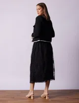 Chaqueta de tweed negra marca Nanette, con escote a la base, abertura central con botones, bolsillos delanteros, aplique de botones perlados en los puños, ribete en contraste blanco y forro interno.