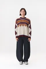 Buzo de tejido de punto con diseño geométrico y combinación de colores en contraste. Presenta cuello redondo, mangas largas y corte oversized.