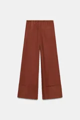 Pantalón palazzo de tiro alto, color beige claro, confeccionado en lino 100%. Presenta cintura ajustable con cordones anudados al frente y pierna ancha.