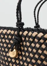 Bolso tipo tote confeccionado con un diseño trenzado en colores negro y beige. Cuenta con doble asa de mano trenzada y detalles metálicos dorados.