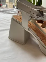 Sandalias de cuero color gris claro con taco cuadrado y tobillera ajustable.