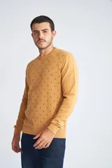 Sweater de punto color mostaza con cuello redondo y mangas largas. Presenta un estampado de pequeños motivos repetidos en contraste y un logo bordado en el pecho.