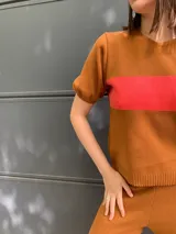 Sweater marrón de tejido de punto con una franja horizontal roja en el pecho y mangas cortas abullonadas.