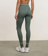 Legging deportiva color verde, confeccionada en poliamida, con cintura baja y rayas horizontales en blanco y gris.