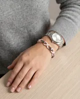 Pulsera de eslabones de acero inoxidable alternados con dijes de cerámica en forma de infinito color rosado.
