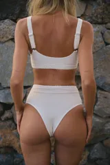 Conjunto de bikini blanco de lycra texturada, compuesto por un corpiño tipo top con breteles regulables y una bombacha de tiro alto.