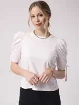 Remera blanca de algodón con mangas abullonadas de plumeti y lazos ajustables en los puños.
