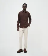 Camisa de corte slim, manga larga, con cuello camisero y cierre frontal de botones. Confeccionada en tejido plano de bambú, viscosa, poliéster y elastano.