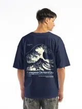 Remera de corte oversized color azul marino, con estampa gráfica minimalista en el pecho que incluye una ilustración de una ola y texto tipográfico.