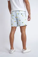 Short de baño con cintura elástica y cordón ajustable, confeccionado en tela ligera de secado rápido. Presenta un estampado botánico integral en tonos amarillos, blancos y azules, con dos bolsillos delanteros y uno posterior.