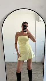 Vestido corto color amarillo pastel, strapless, con frunces laterales y falda con volados.