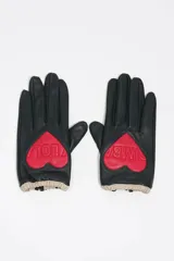 Guantes de piel negra con detalle de corazón rojo en el dorso que incluye el logo grabado. Presentan puños elásticos en color beige.