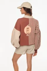 Cardigan tejido bicolor en tonos verde y crudo, con diseño de rayas verticales en la mitad derecha y liso en la izquierda. Presenta cuello en V, cierre frontal con botones y mangas abullonadas con puños ajustados.