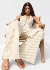 Pantalón de vestir de tiro medio con diseño de rayas verticales en tono beige y crudo. Presenta pernera recta y holgada, con pinzas delanteras y bolsillos laterales.