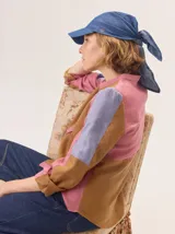 Gorro tipo pañuelo con visera rígida azul marino, confeccionado en lino con estampado de rayas grises y blancas. Presenta un diseño envolvente con caída trasera y detalle de logo bordado en el lateral.