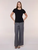 Remera básica de corte al cuerpo con textura acanalada, cuello redondo y mangas cortas. Presenta una pequeña placa metálica decorativa en el borde inferior.