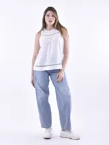 Blusa blanca sin mangas con cuello redondo, confeccionada en tela liviana con detalles de bordado inglés en el canesú y en el ruedo.
