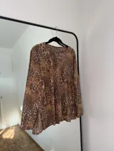 Sweater de punto con estampado animal print, de corte holgado, cuello redondo y mangas largas con aberturas laterales en el ruedo.