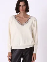 Sweater color crema de tejido de punto, con escote en V y detalle de cadena plateada con strass en el borde del escote.