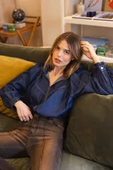 Camisa de denim azul con costuras a la vista en color contrastante, cuello camisero, mangas largas abullonadas con puños abotonados y corte holgado.