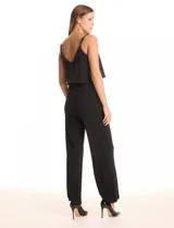 Enterito negro de crepe con escote en V, breteles finos ajustables y una capa suelta en la parte superior. La cintura es definida con corte anatómico y el pantalón tiene pierna ancha de caída fluida. Cierre invisible en la espalda.