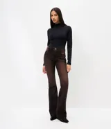Pantalón de jean corte flare con lavado sobretinta en tono marrón oscuro. Presenta cintura media con trabillas, cierre frontal con cremallera y botón, cinco bolsillos funcionales y ruedo deshilachado.