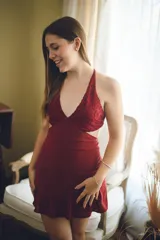 Vestido corto negro con estampado de plumas doradas, escote en V, breteles finos cruzados en la espalda, cut-outs laterales y volado en el ruedo.