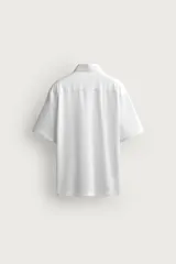 Camisa azul marino de corte regular fit confeccionada en tejido fluido de algodón y lino, con cuello solapa, manga corta, bolsillo aplicado en el pecho y cierre frontal con botones.