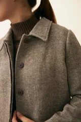 Tapado con cuello solapa y corte recto, color gris. Cierre frontal con botones ocultos, tajos laterales y bolsillos escondidos en corte lateral. Con forro. Tela 100% lana fina sin teñir, diseñada exclusivamente por Don Baez. Hecha 100% en Uruguay.