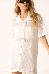 Vestido corto blanco de tejido calado con cuello tipo polo, mangas cortas y cierre frontal con botones.